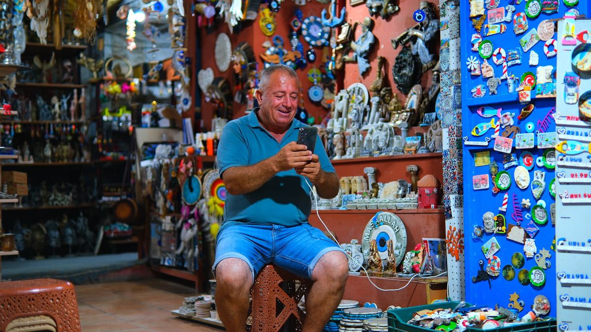 Un negoziante seduto nel suo negozio che guarda il telefono